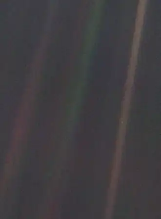 Dark grey and black static with coloured vertical rainbow beams over part of the image. A small pale blue point of light is barely visible.